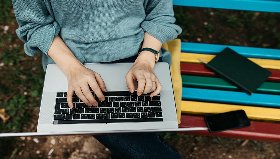 sitting on colourful bench with laptop