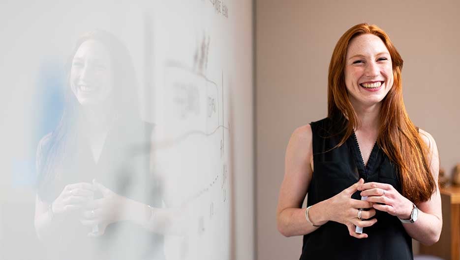 smiling woman standing near whiteboard