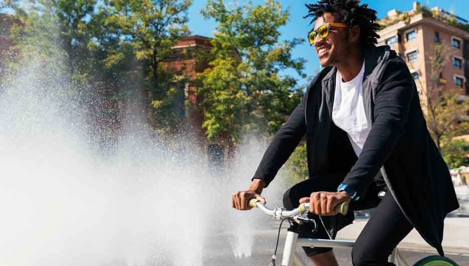 Handsome afro man riding a bike in the street.