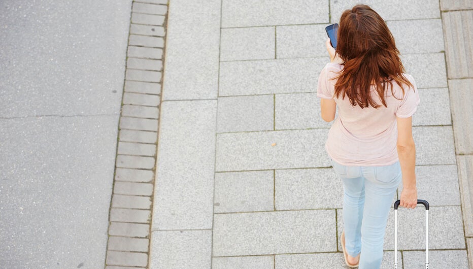 woman walking with phone and suitcase