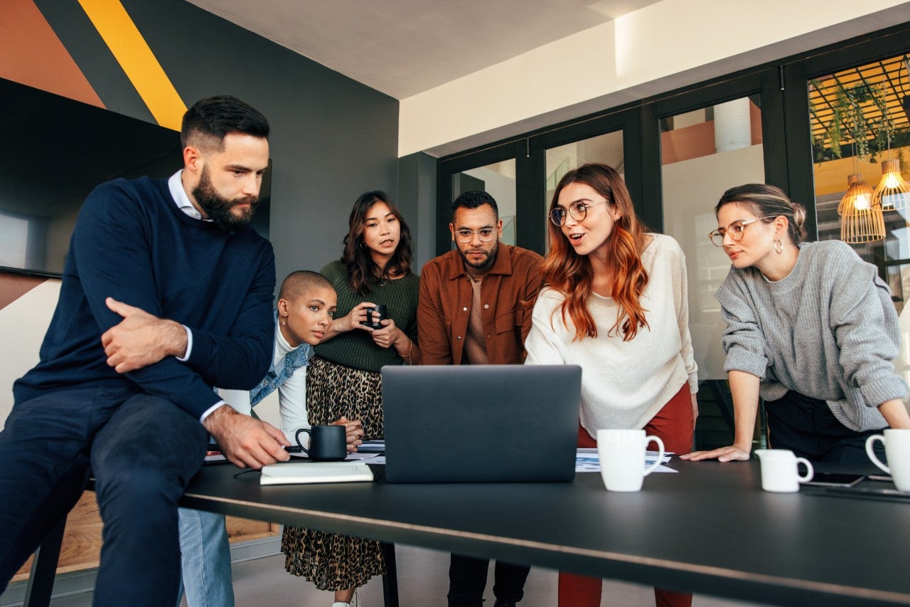 Group of businesspeople having a discussion in a boardroom. Group of multicultural businesspeople looking at a laptop screen in a modern office. Young entrepreneurs collaborating on a new project.
