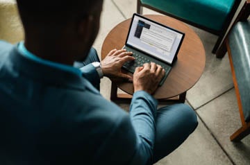 Image of thinking african american woman working with laptop and