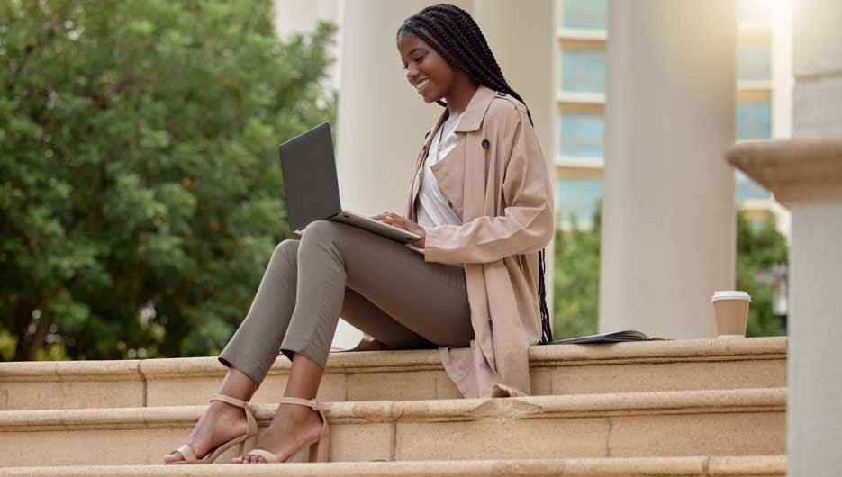 Steps, city and black woman typing on laptop in street, social media or internet browsing. Technology, computer or happy remote worker or business female working on research, email or project in town