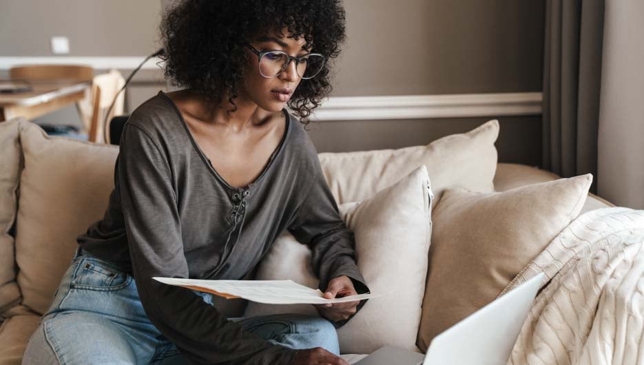 Image of thinking african american woman working with laptop and